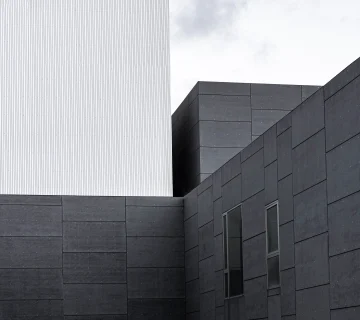 اجرای نمای سیمان آبساب در ساختمان مدرن با بافت تیره و روشن، نمایش سطوح یکدست و خطوط دقیق در طراحی نما