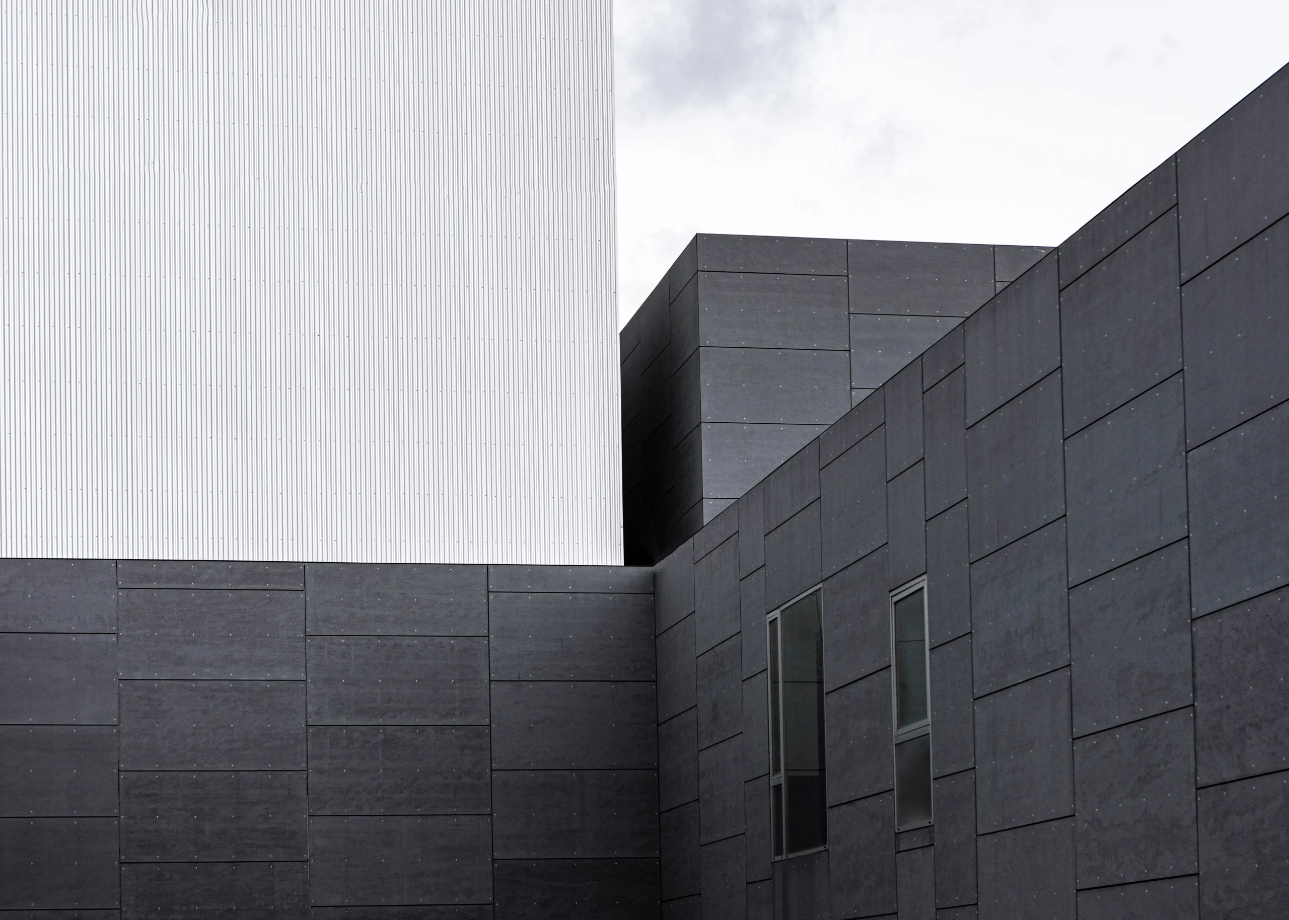 اجرای نمای سیمان آبساب در ساختمان مدرن با بافت تیره و روشن، نمایش سطوح یکدست و خطوط دقیق در طراحی نما