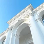 اجرای نمای رومی با سیمان ساختمان ساخته‌شده با سیمان سفید، شامل ستون‌ها و قوس‌های تزئینی که ترکیبی از شکوه کلاسیک و زیبایی معماری مدرن را به نمایش می‌گذارد.