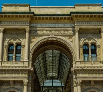 طراحی نمای رومی ساختمان با قوس بزرگ مرکزی، ستون‌های کلاسیک و تزئینات سنگی پیچیده که نمادی از شکوه، اصالت و معماری باستانی رومی است.